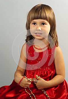 Cute little girl in a red dress with necklace in h