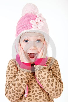 Cute little girl in red hat holding hands to face in surprise