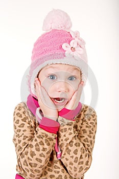 Cute little girl in red hat holding hands to face in surprise