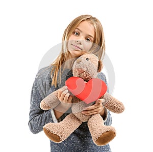 Cute little girl with red heart and teddy bear on white background