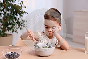 Cute little girl refusing to eat her breakfast at home