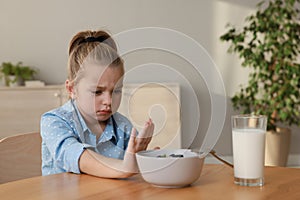 Cute little girl refusing to eat her breakfast at home