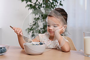 Cute little girl refusing to eat her breakfast at home