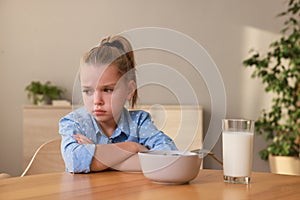 Cute little girl refusing to eat her breakfast at home