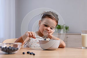 Cute little girl refusing to eat her breakfast at home