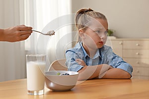 Cute little girl refusing to eat her breakfast at home