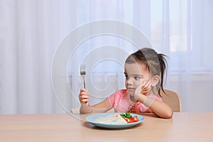 Cute little girl refusing to eat her breakfast at home, space for text