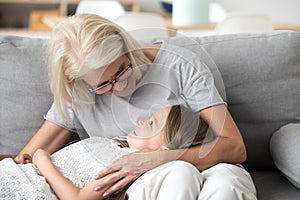 Cute little girl relax on granny knees relaxing at home