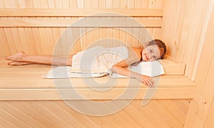 Cute little girl relaxing on bench at sauna