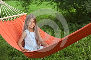 Cute little girl relaxing in hammock on summer day