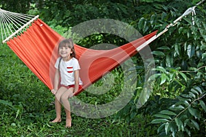 Cute little girl relaxing in hammock on summer day