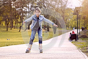 Young girl rides inline skating rollerblades in the park
