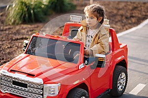 Cute little girl rides in a mini city on a red electric car jeep. Adorable little girl road in toy city. Plays for