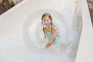 Cute little girl riding down a water slide at a water park