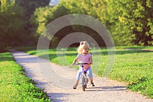 Cute little girl riding first bike in summer nature