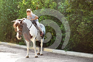 Cute little girl riding pony in park