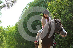 Cute little girl riding pony in park