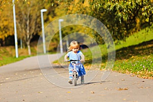 Cute little girl riding runbike in autumn