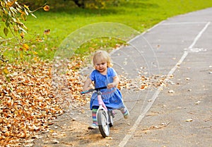 Cute little girl riding runbike in autumn