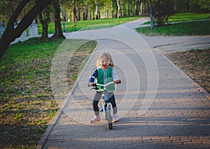 Cute little girl riding runbike in park, active kids