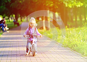 Cute little girl riding runbike in park, kids