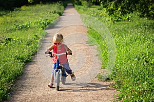 Cute little girl riding runbike in summer