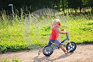 Cute little girl riding runbike in summer