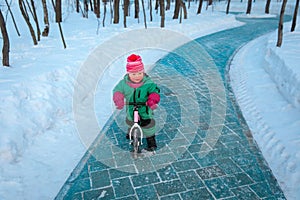 Cute little girl riding runbike in winter nature