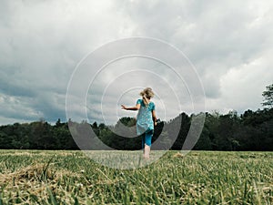 Cute little girl run on meadow. Kids girl legs feet in rain boots. Freedom innocence and adolescense concept. Summer fun outdoors