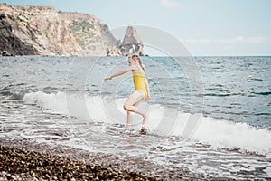 Cute little girl running along the seashore against a clear blue