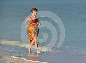 Cute little girl running on beach in sunset