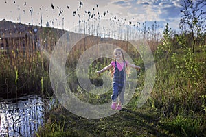 Cute little girl running through a beautiful meadow near the lake, lifestyle after lockdown
