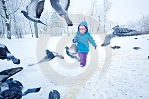 Cute little girl running and frightens pigeons