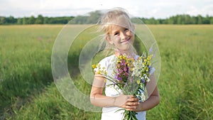 Cute little girl running in a meadow in the colors of a flowers. Carefree childhood - little child girl play on summer