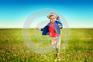 Cute little girl running on meadow in a field.