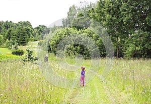 Cute little girl running on a meadow at summer in the countryside.