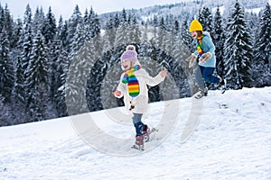 Cute little girl running on snow winter nature. Funny kid playing with snow in winter clothes. Children winter outdoors