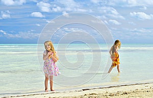 Cute little girls on sandy beach in sunset light
