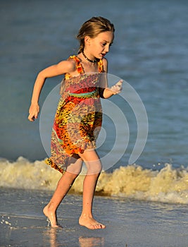 Cute little girl on sandy beach in sunset light.