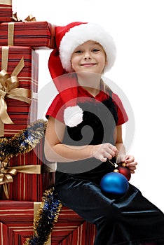 Cute little girl in a Santa Claus cap with Christmas gifts, isolated