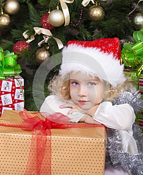 Cute little girl in Santa's hat with big Christmas gift