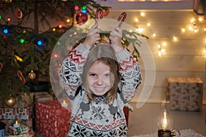 Cute little girl in a Scandinavian sweater at the Christmas tree.