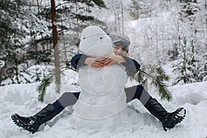 Cute little girl sculpts snowman in winter snowy Park photo