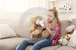 Cute little girl sharing her tea with her friend teddy bear