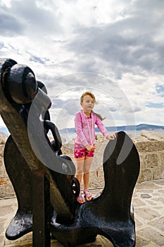 Cute little girl with ship anchor on the seaside