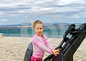 Cute little girl with ship anchor on the seaside