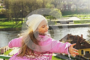 Cute little girl shone with happiness, curly hair, charming smile in the sunny spring day