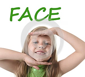 Cute little girl showing face in body parts learning English words at school