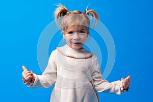 Cute little girl showing thumb up on blue background