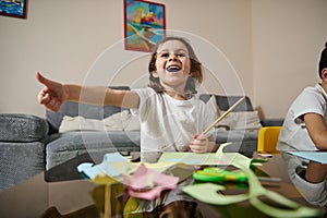 Cute little girl showing thumb up and expressing happiness during creative hobby at home